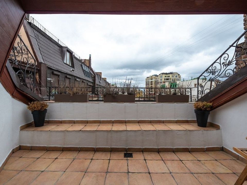 Terrasse carrelée en grès cérame posée sur plots en balcon au-dessus du dénivelé d'une maison de coteau de Caluire, avec vue sur la vallée
