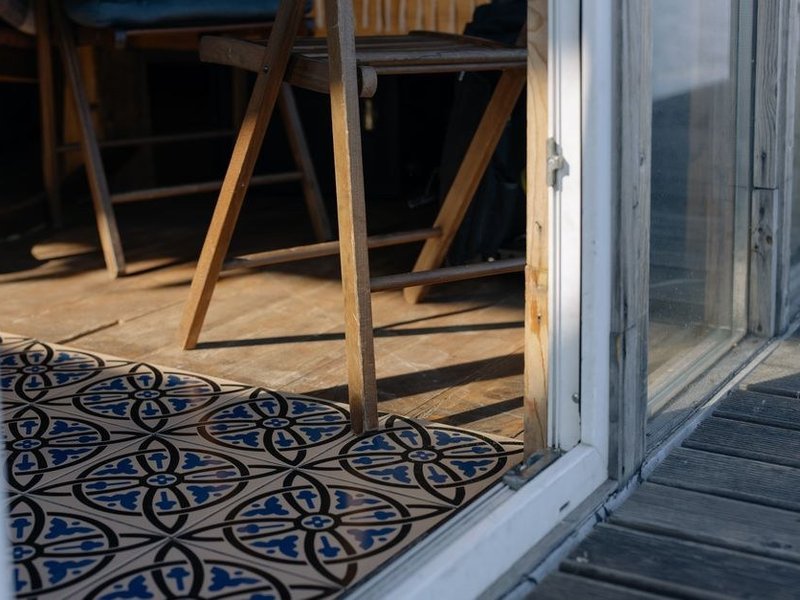 Séjour d'une maison du village de Couzon carrelé en carreaux de ciment à motifs anciens, posés sur un support ragréé, raccord soigné avec le seuil d'origine