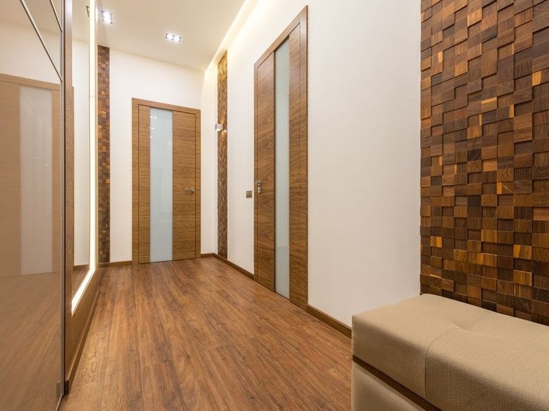 Jonction nette entre le carrelage du couloir et le parquet d'une chambre dans une maison modeste de Grigny