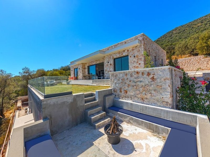 Terrasse de plain-pied d'une villa de Limonest carrelée en grès cérame effet pierre dans la continuité du séjour, dominant les coteaux boisés des Monts d'Or