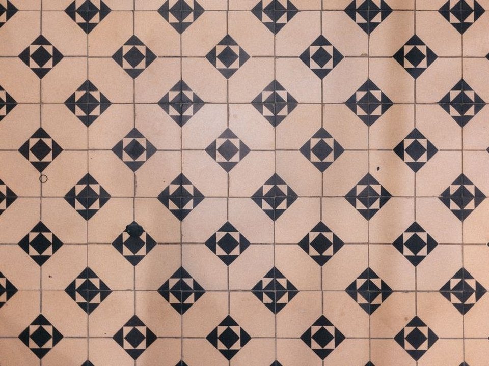 Anciens carreaux de ciment à motifs géométriques repris au sol du séjour d'une maison de bourg ancienne d'Oullins