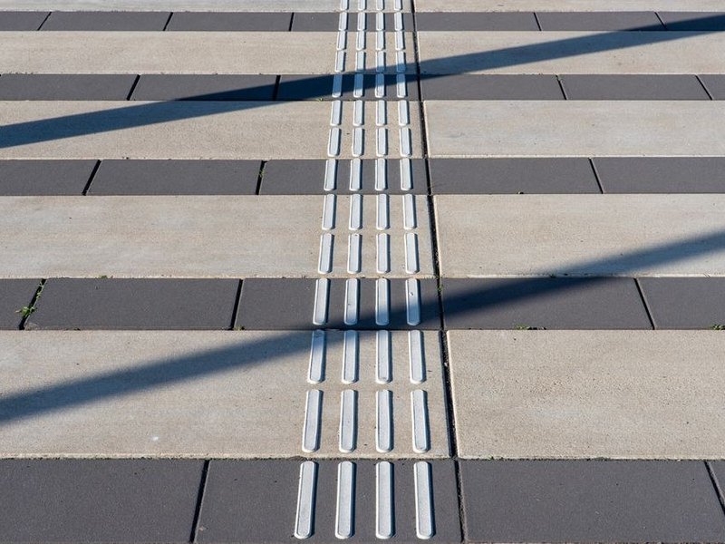 Terrasse carrelée en grès antidérapant côté jardin d'un pavillon de plain-pied sérézinois, dans le prolongement du séjour au même niveau