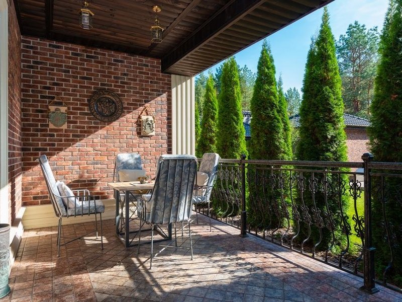 Terrasse d'une maison de coteau à Solaize dominant le Rhône, dalle sur plots réglée à la pente dans la continuité du séjour, seuil de baie soigné