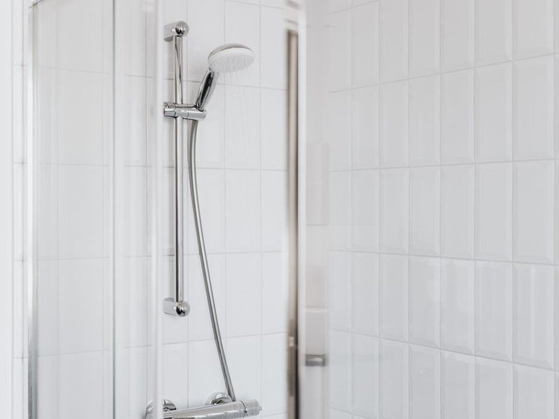 Pose d'une faïence murale blanche simple et solide dans une salle de bain d'appartement de grand ensemble à Vénissieux, joints réguliers alignés avec le sol