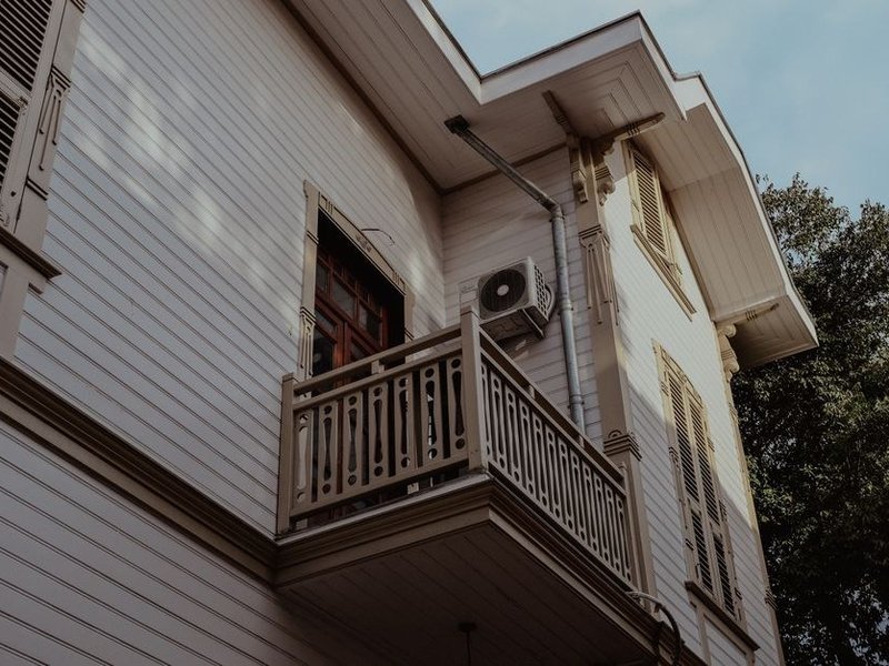 Unité extérieure de pompe à chaleur air-eau posée le long d'une façade sur un terrain en pente à Caluire-et-Cuire