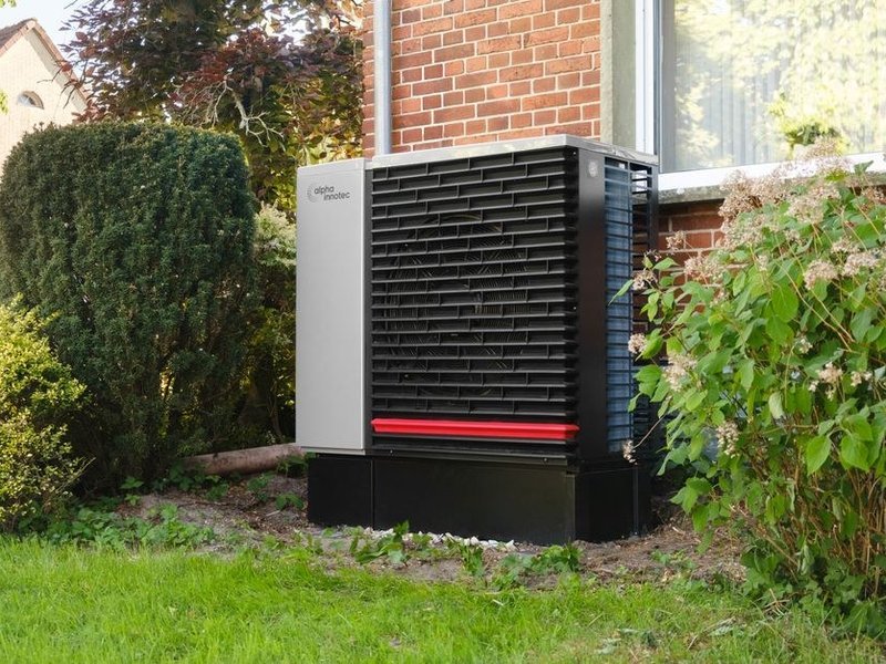 Unité extérieure de pompe à chaleur air-eau installée dans le jardin paysager d'une villa de standing à Écully