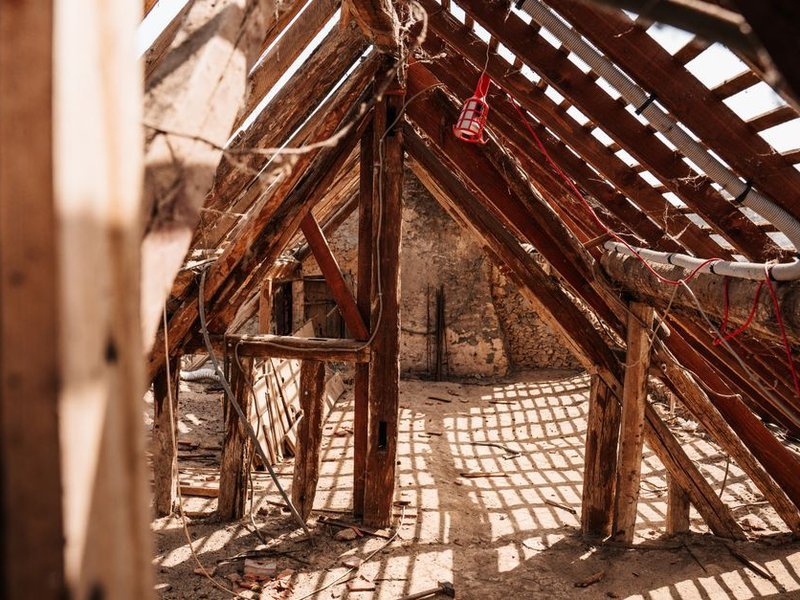 Reprise ponctuelle d'un chevron de charpente bois ancienne noirci par l'humidité sous la couverture déposée d'une maison de Brignais