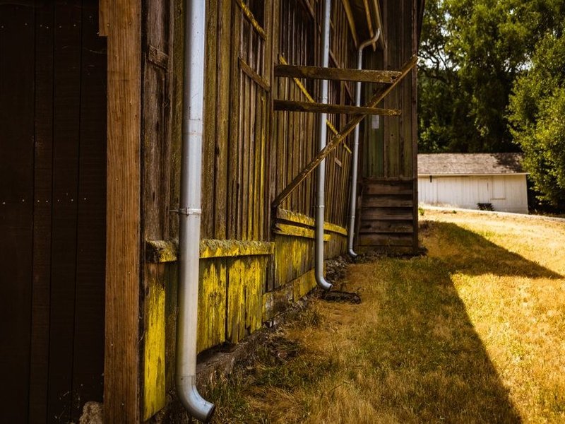 Descente et gouttière reprises le long d'un bâtiment ancien du bourg de Fontaines-sur-Saône, échafaudage en place