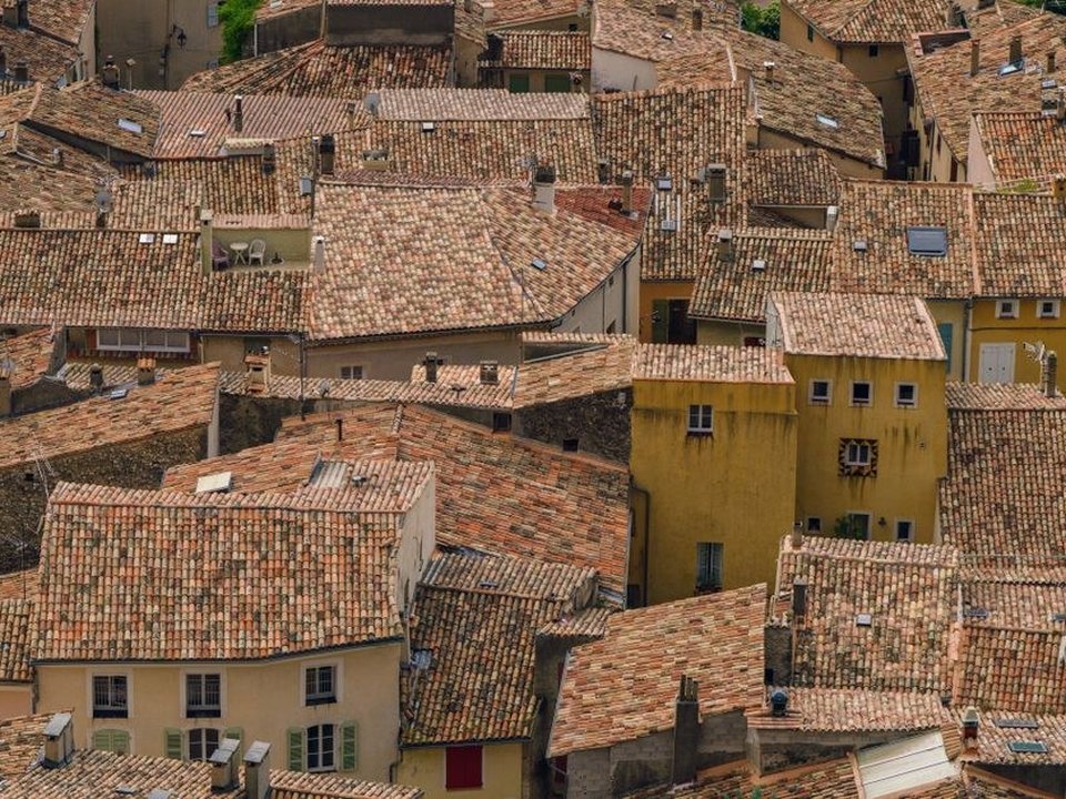 Couvreur reprenant la toiture en tuile d'une maison de ville ancienne du bourg de Grigny