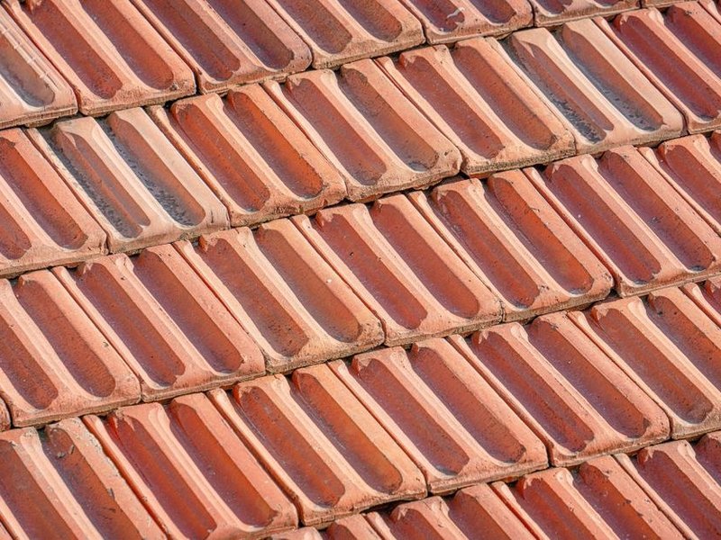 Pose de tuiles neuves sur le versant à petite pente d'une maison de ville de Montchat à Lyon 3 pendant la réfection de la toiture