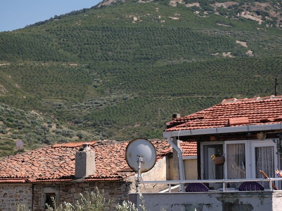 Toiture en tuile de pays d'une maison de pierre du bourg de Montagny accrochée au coteau, versants décalés dominant la vallée