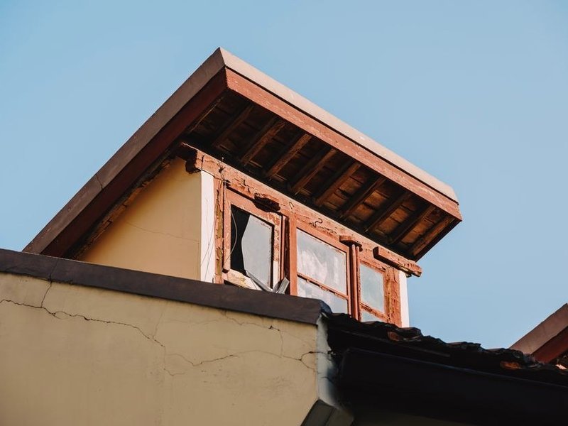 Contrôle de la charpente ancienne en bois dans les combles d'une maison en pierre du bourg de Mornant, chevrons et pannes examinés