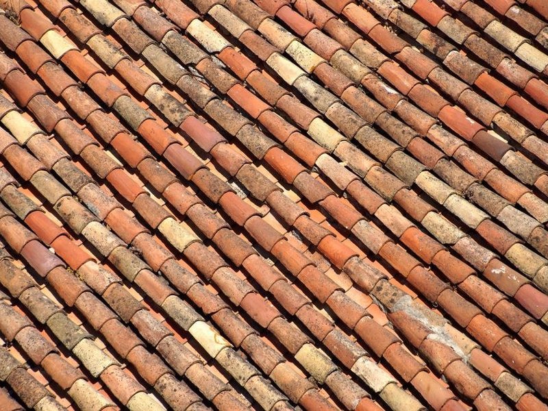 Repose d'une tuile de pays réemployée sur le versant d'une haute maison du centre ancien de Saint-Symphorien-sur-Coise pendant la réfection