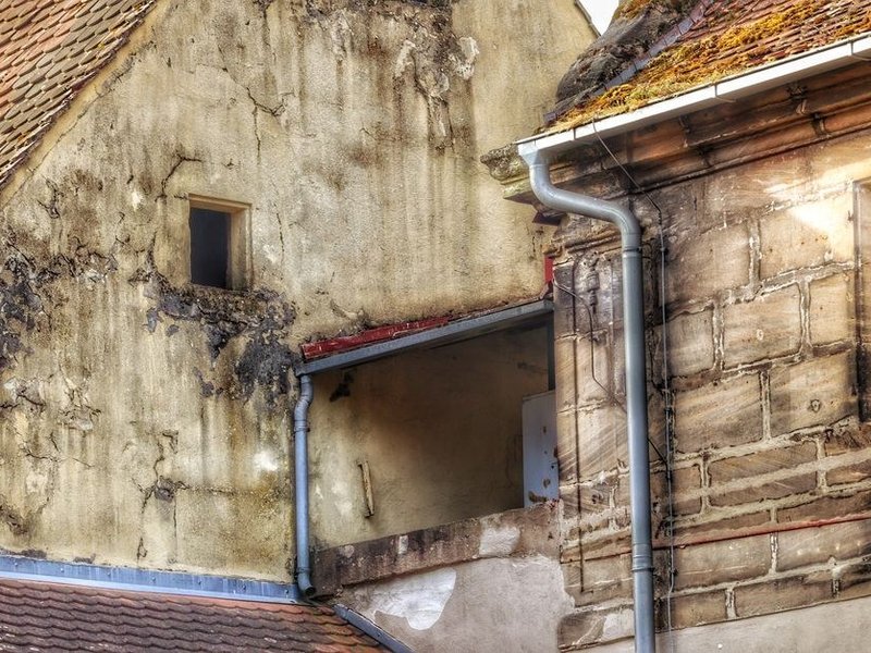 Infiltration le long d'un solin sur un toit ancien en pierre du bourg de Thurins avant travaux