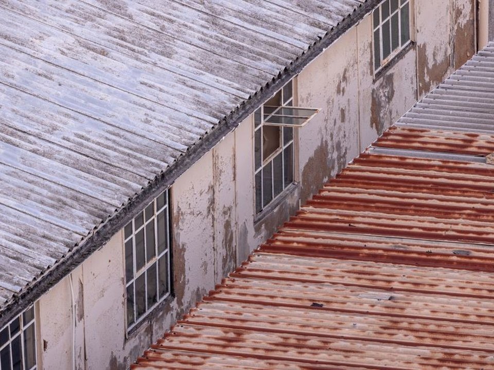 Couvreur intervenant sur une toiture en shed d'une ancienne usine de soie réhabilitée au Carré de Soie à Vaulx-en-Velin
