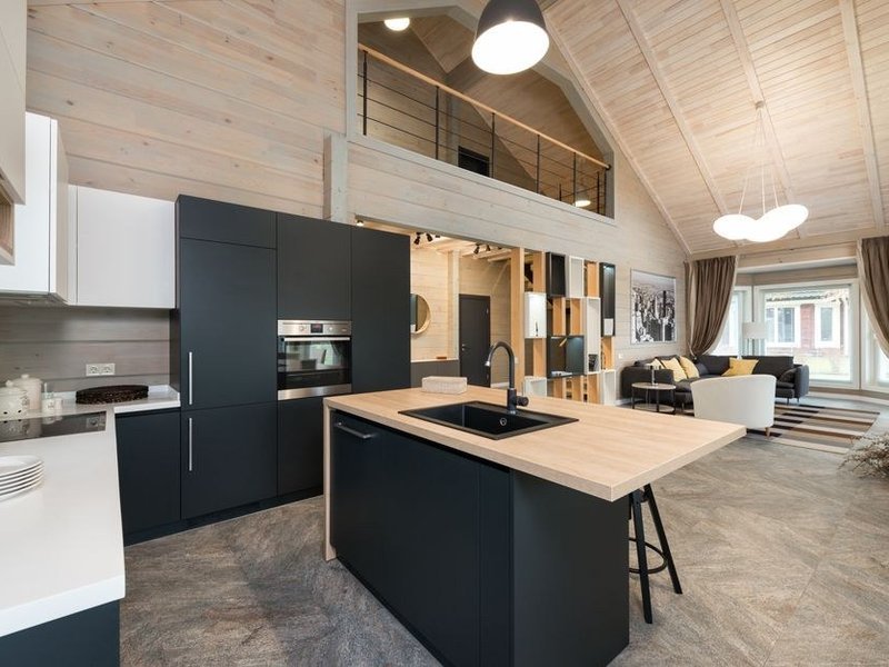 Cuisine de réception dans une demeure bourgeoise de Brindas reliée au séjour par une verrière d'atelier, îlot à l'échelle de la pièce, plan de travail en matière noble, grande hauteur sous plafond