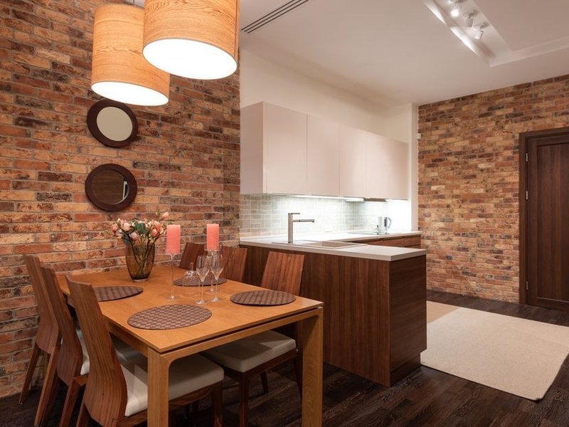 Cuisine sur mesure posée contre un mur de brique et de pierre dans une maison de bourg de Chaponost, coin repas attenant
