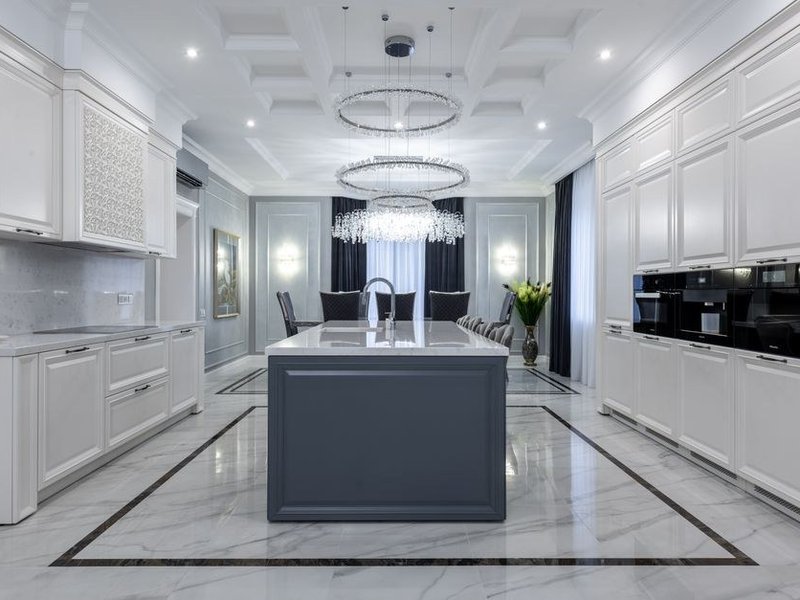 Cuisine sur-mesure avec îlot central dans le grand volume d'une villa Belle Époque à Charbonnières-les-Bains, colonnes toute hauteur sous la corniche et finitions haut de gamme
