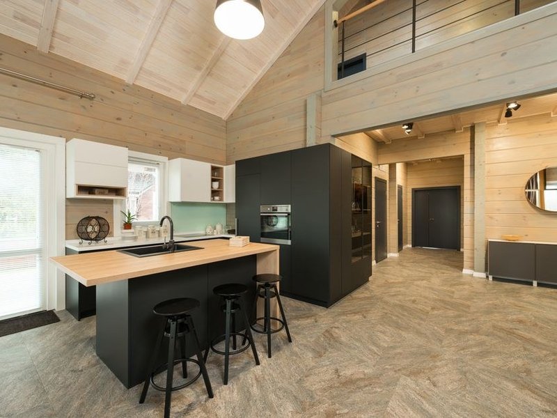 Cuisine de pavillon de hameau sur un versant boisé de Courzieu, bois clair et teintes douces, ventilation soignée contre l'humidité de sous-bois, séjour ouvert sur la forêt