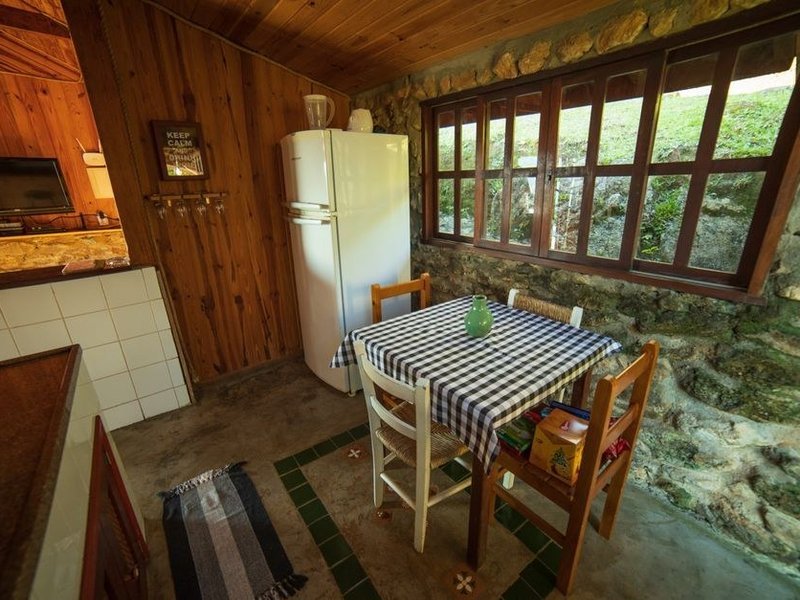 Cuisine sur mesure dans une basse maison de pierre du val de Courzieu, meubles ajustés aux murs épais irréguliers, pierre laissée apparente en fond, recoins récupérés en rangement