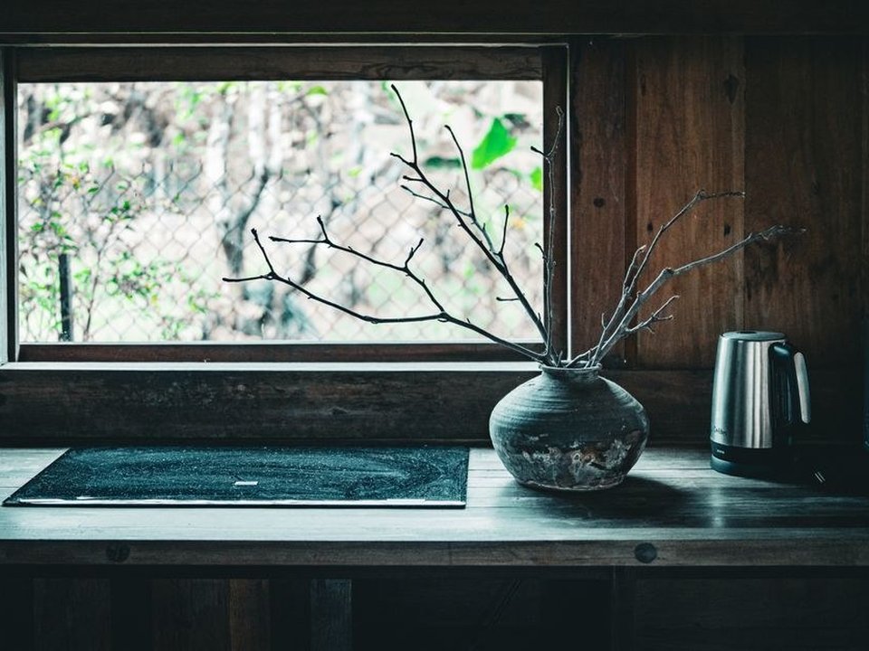 Cuisine tournée vers la fenêtre qui capte le jour dans une maison de pierre du fond de vallée boisée à Courzieu, bois clair et plan de travail lumineux face à la clarté des versants forestiers