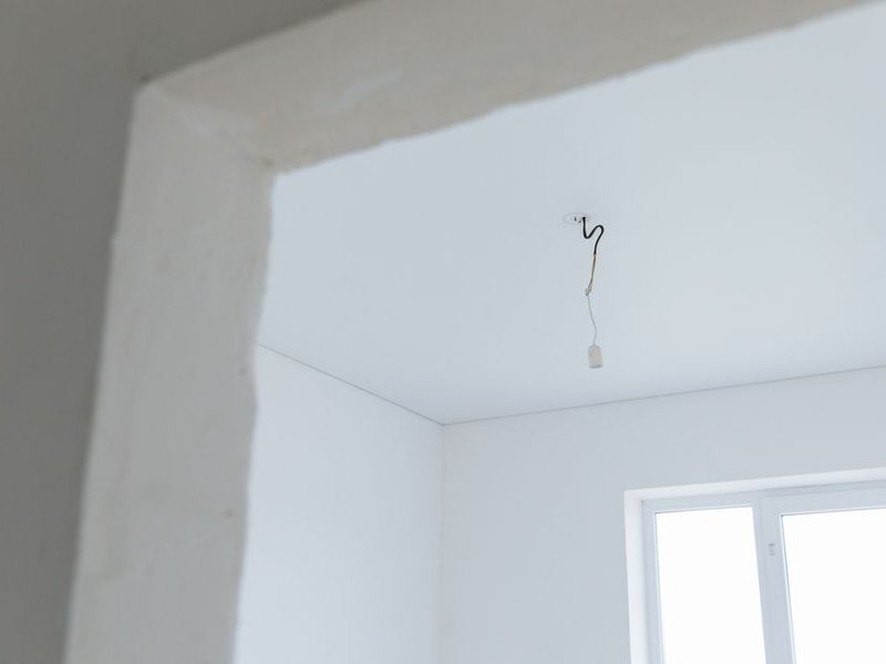 Attentes techniques laissées par le promoteur dans un appartement neuf de Décines, arrivée d'eau et évacuation bouchonnées et attente électrique en fils sortant du mur, sur une pièce nue avant la pose de la cuisine