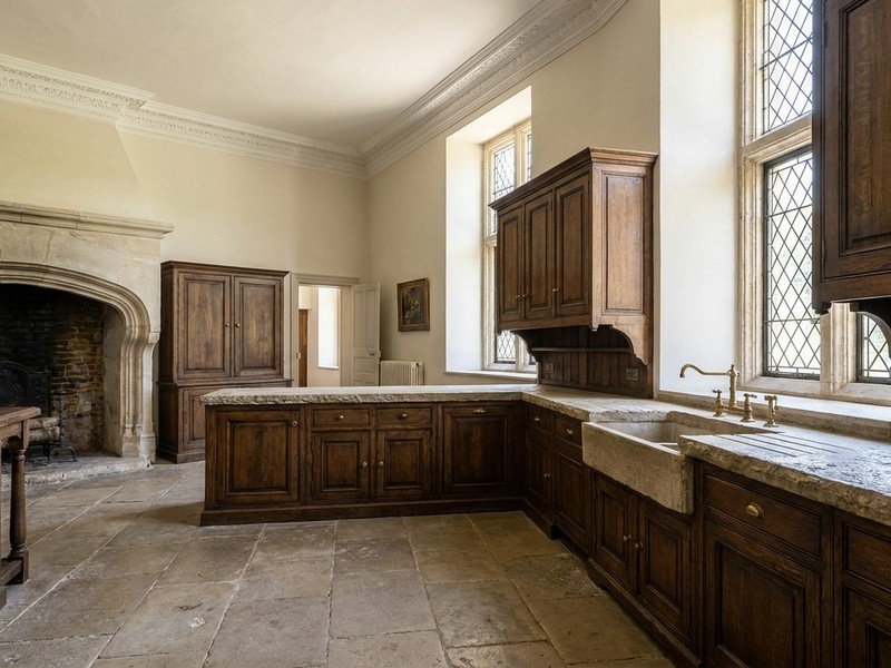 Cuisine sur mesure en bois massif posée dans une belle maison ancienne cossue d'Écully aux grands volumes, hauteur sous plafond et moulures, plan de travail en pierre