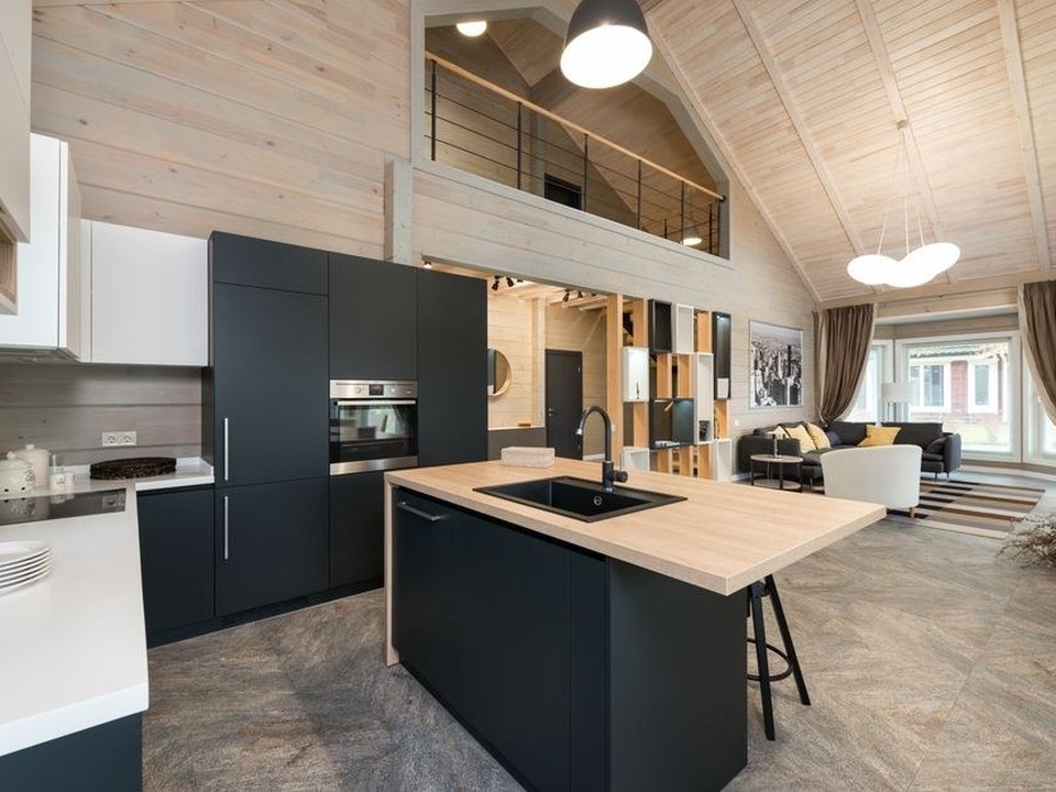 Cuisine à îlot central ouverte sur le séjour et la terrasse dans un pavillon de lotissement à Genas, grand plan de travail familial, baie donnant sur le jardin de plain-pied, implantation libre sans contrainte de copropriété