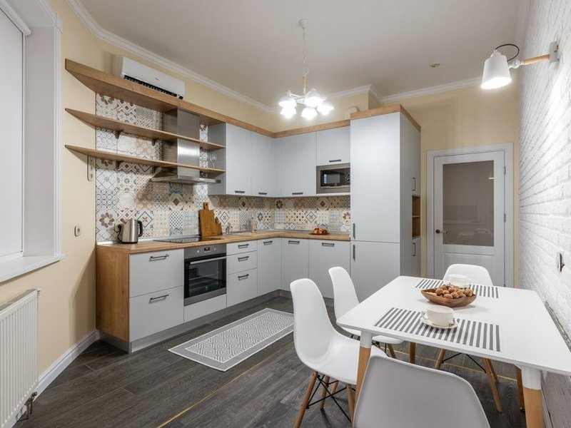 Petite cuisine modernisée d'une maison de bourg ancienne de Grézieu-la-Varenne, meubles ajustés aux murs de travers, rangements montés en hauteur, teintes claires, centre du village