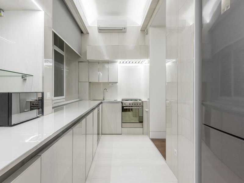 Cuisine sur mesure posée en I dans une maison de ville étroite de La Mulatière, meubles ajustés entre deux murs et colonnes toute hauteur pour gagner du rangement sans bloquer le passage