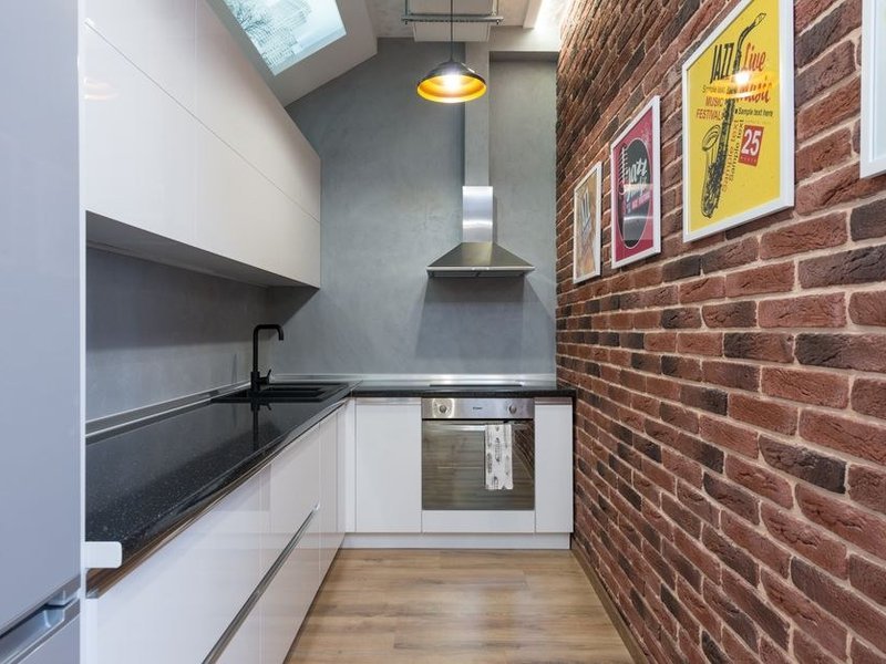 Cuisine compacte modernisée dans un appartement ancien de coteau à La Mulatière, façades claires et éclairage intégré pour capter la lumière d'un volume fermé et serré