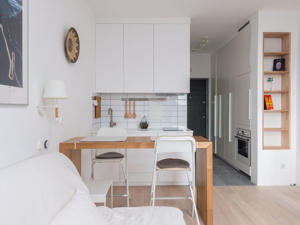 Cuisine étroite agencée sur mesure dans une maison de ville en pente de La Mulatière, meubles ajustés entre deux murs anciens et plan de travail continu qui rattrape les angles pas droits d'un logement de coteau