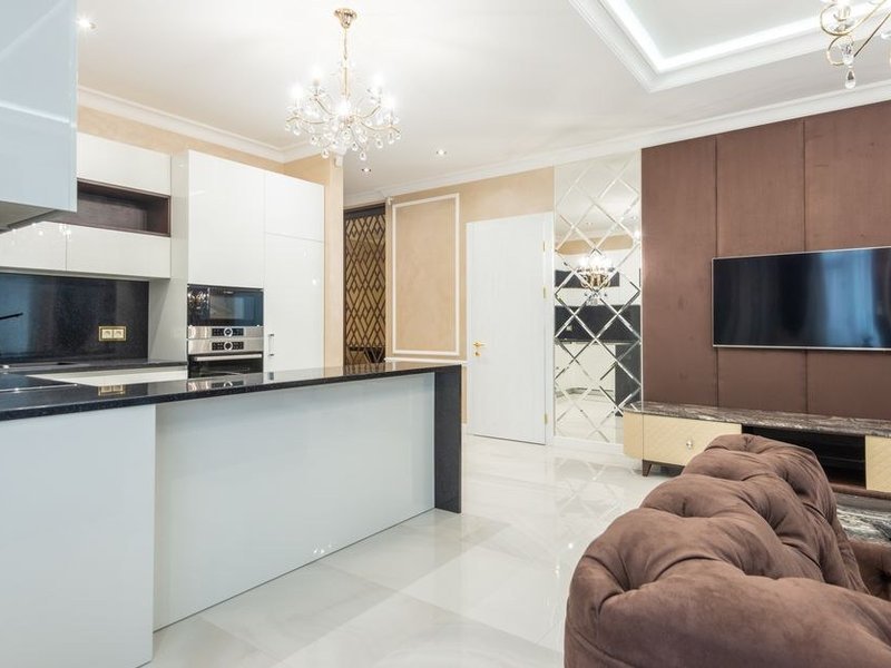 Cuisine ouverte sur le séjour d'un appartement ancien de Bellecour à Lyon 2 après ouverture d'une cloison porteuse étudiée en copropriété, moulures raccordées et cuisine sur mesure intégrée sous une belle hauteur sous plafond
