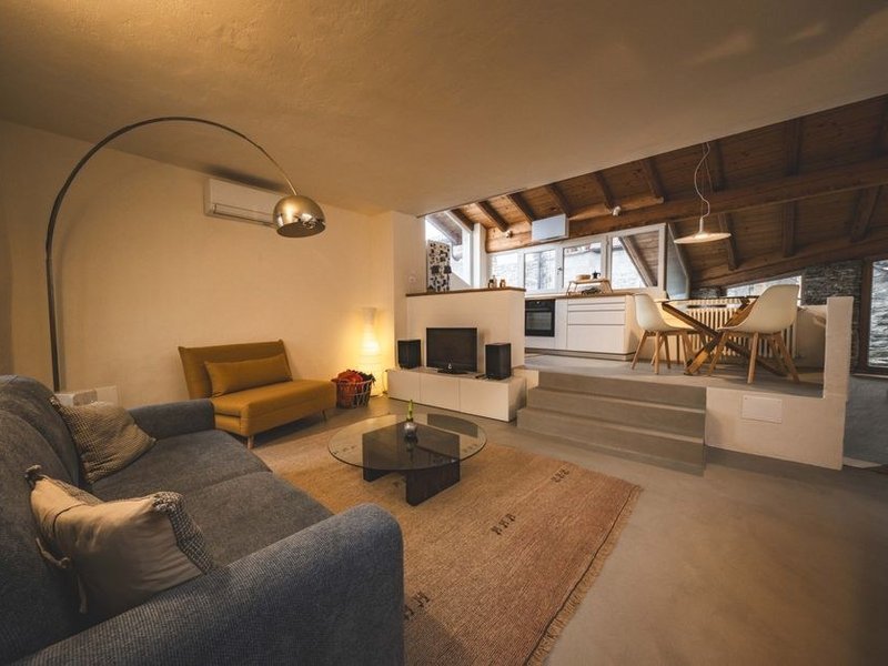 Cuisine ouverte sur le séjour dans un appartement du Vieux-Lyon à Lyon 5, pan de mur en pierre gardé apparent en fond, meubles ajustés aux murs anciens qui ne sont pas d'équerre