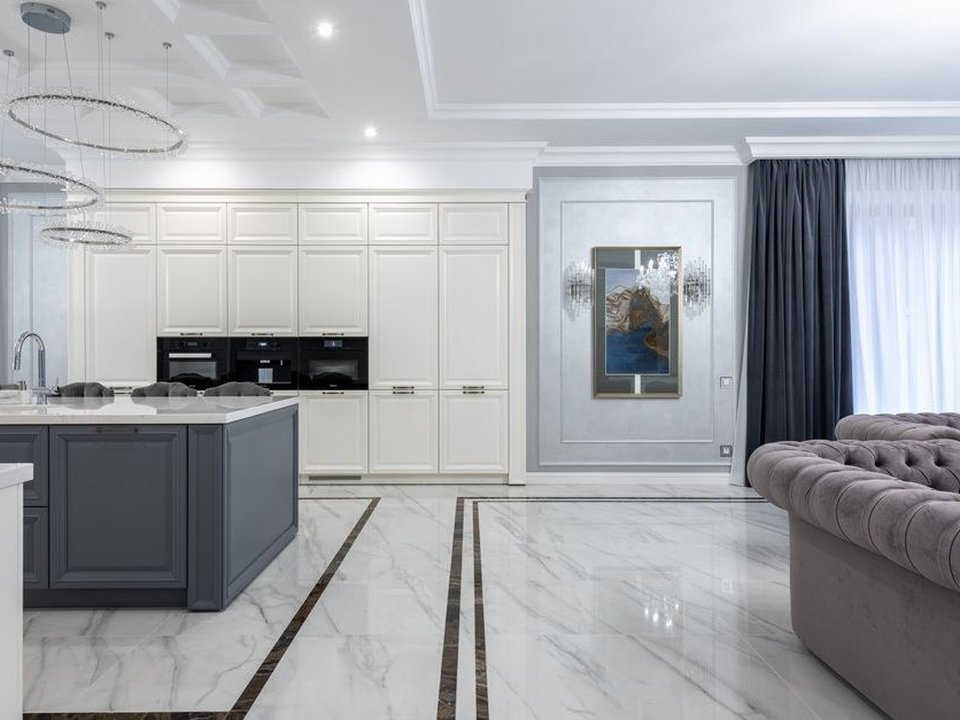 Cuisine sur mesure haut de gamme dans un grand appartement haussmannien des Brotteaux à Lyon 6, ouverte sur le séjour de réception, moulures, corniches et parquet point de Hongrie préservés sous une grande hauteur sous plafond