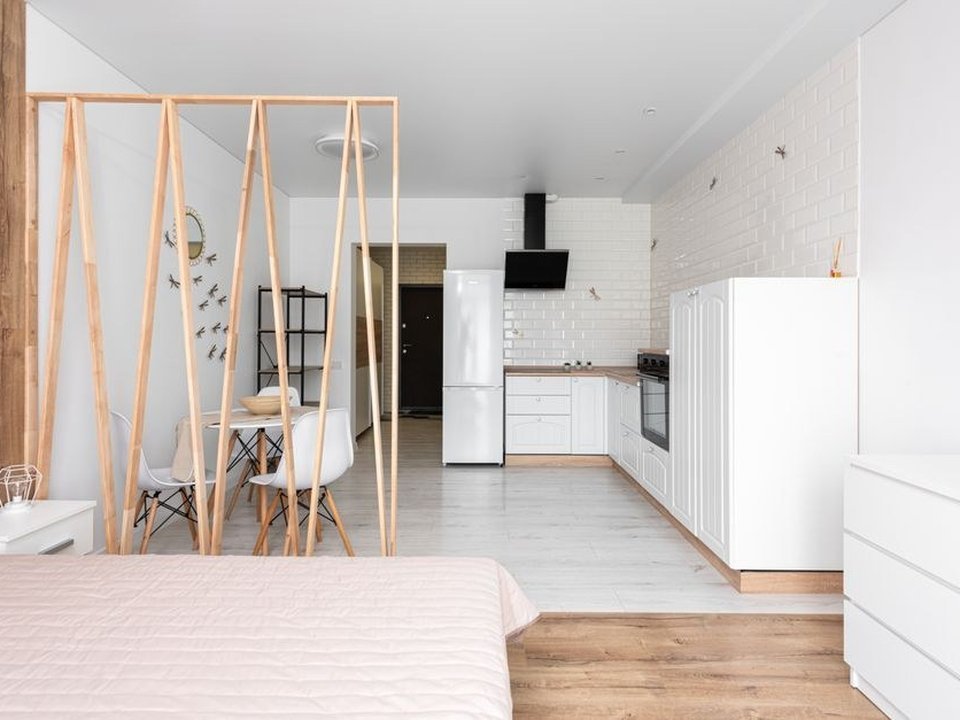 Petite cuisine compacte optimisée dans un studio locatif de la Guillotière à Lyon 7, meubles alignés en I le long d'un mur, colonnes de rangement montées jusqu'au plafond et électroménager encastré compact