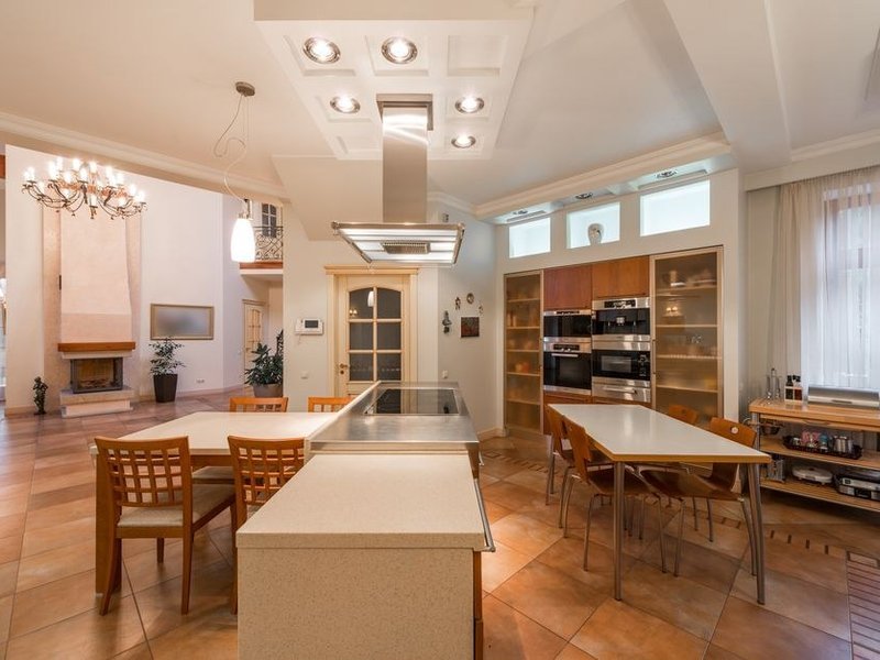 Cuisine d'un pavillon de lotissement récent de Marcy-l'Étoile, implantation revue, évier face à la baie et coin repas tourné vers le jardin arboré, meubles hauts placés pour laisser passer la lumière