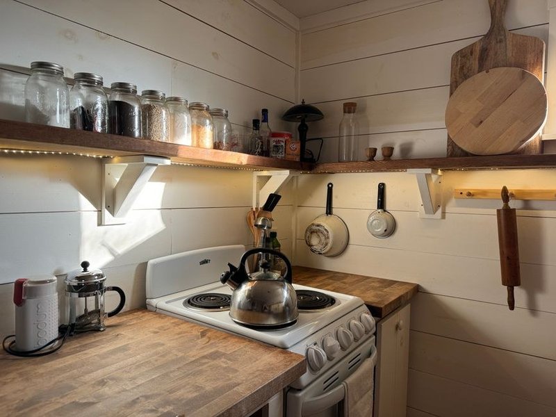 Cuisine d'une maison de pierre de Montrottier réagencée pour gagner de la place, rangements montant vers la hauteur, cloison légère retirée vers la pièce voisine, mur de pierre laissé apparent