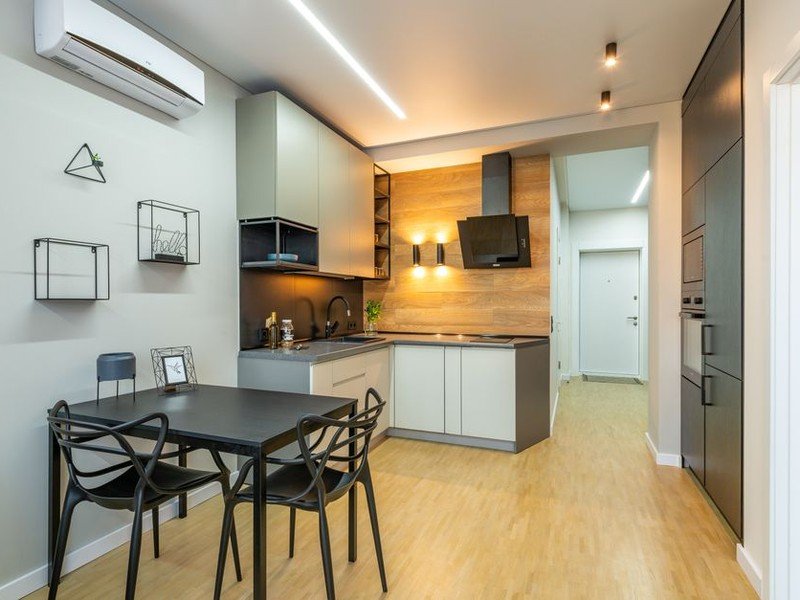 Cuisine étroite en longueur réaménagée le long d'un seul mur dans une maison de ville ancienne d'Oullins, meubles bas et hauts continus et plan de travail filant