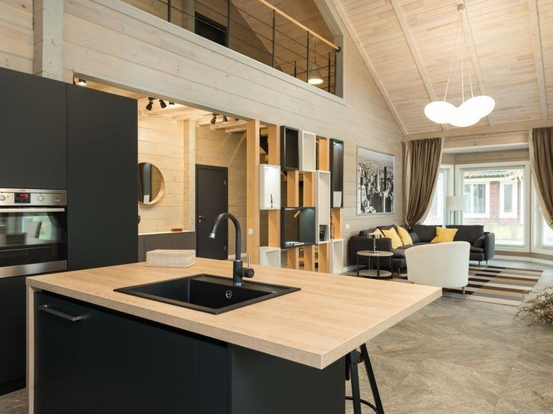 Cuisine ouverte sur le séjour dans une maison de bourg de Pollionnay, mur de pierre ouvert et linteau posé, bois clair, pièce à vivre chaleureuse