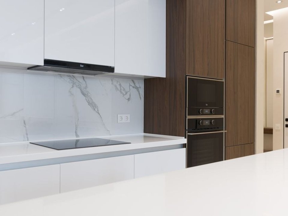 Cuisine équipée réagencée dans un appartement de la ville nouvelle à Rillieux-la-Pape, implantation en L, colonnes toute hauteur sur une pièce fermée du plateau