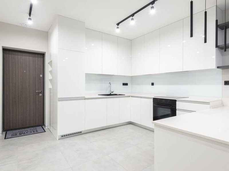 Cuisine étroite d'un appartement de faubourg de Saint-Fons réagencée, colonnes toute hauteur et plan de travail continu exploitant chaque mètre de mur