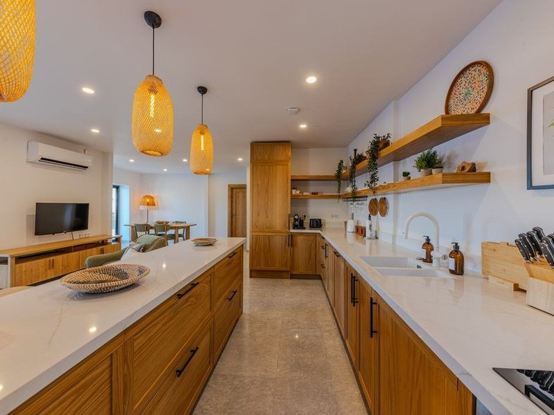 Cuisine sur mesure posée dans une maison mitoyenne en pierre du vieux village de Sathonay-Village, caissons ajustés aux murs épais et rangement plaqué sur le mur aveugle