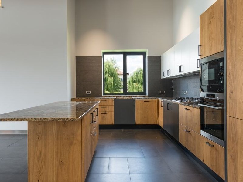 Cuisine sur mesure ajustée aux murs et aux niveaux d'une propriété cossue de coteau à Solaize, meubles calés au relevé sur un sol qui varie