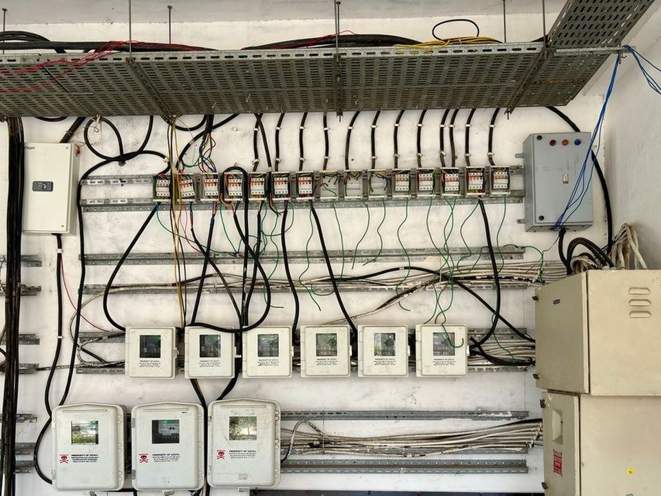 Électricien reprenant un tableau électrique à rail DIN garni de nombreux disjoncteurs modulaires dans le local technique d'une villa de standing à Écully
