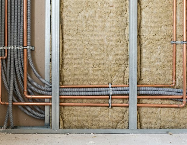 Chantier de rénovation de maison à Lyon, gaines électriques et tuyaux tirés dans des cloisons encore ouvertes