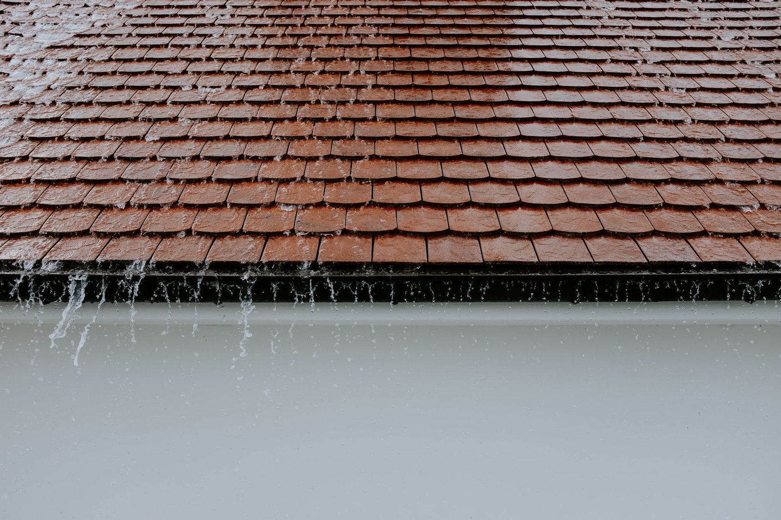 Eau de pluie ruisselant sur une toiture en tuiles à Lyon, risque de fuite en gouttière