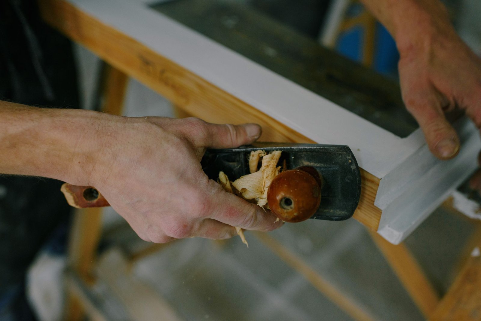 Menuisier à Lyon rabotant un cadre de fenêtre en bois sur mesure