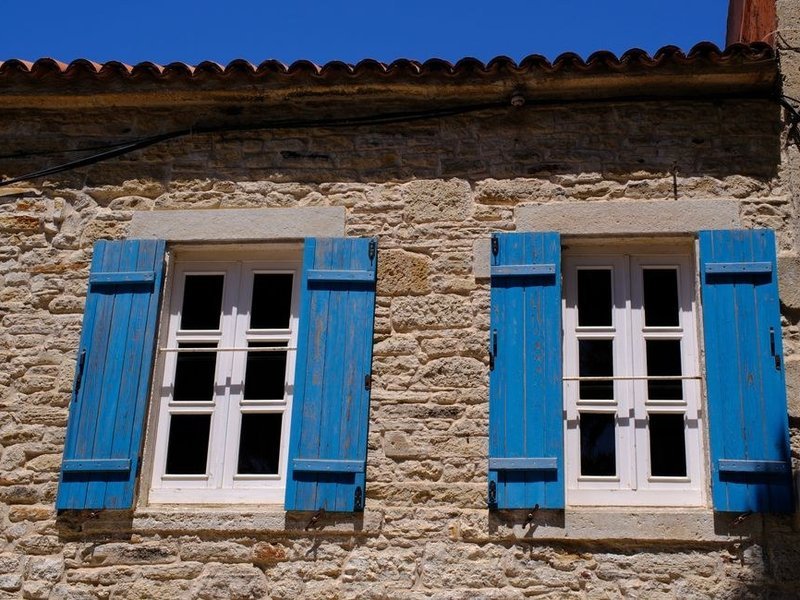 Fenêtres neuves à double vitrage posées sur une maison de bourg de Bessenay, façade claire exposée au soleil le long de la rue