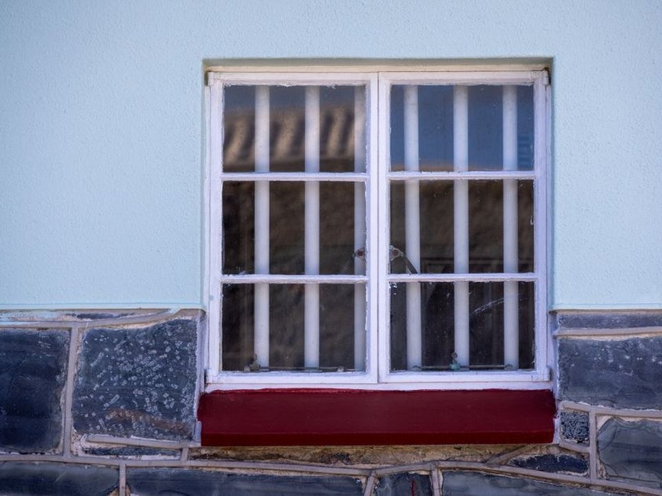 Menuisier posant une fenêtre bois à petits bois sur une maison ancienne en pierre dorée d'une ruelle pentue de Couzon-au-Mont-d'Or